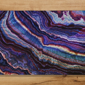 May include: Abstract digital art print featuring a swirling pattern of blue, purple, and red colours. The colours are arranged in a layered, striated pattern, resembling a natural stone or agate.