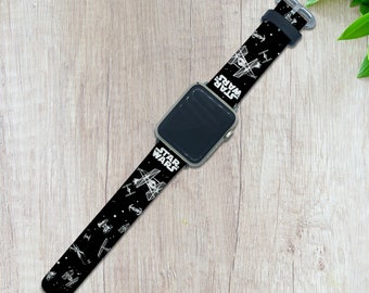 Op de afbeelding: Zwarte Apple Watch band met een wit Star Wars ontwerp met X-Wing gevechtsvliegtuigen en de tekst "Star Wars".
