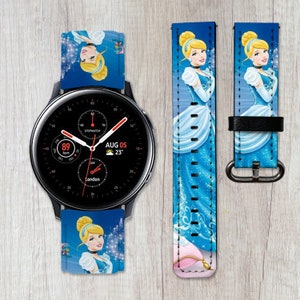 May include: A blue and white watch band with a Cinderella design. The band features a picture of Cinderella in her blue dress and glass slipper. The watch face shows the time, date, and temperature. The text on the watch face reads "AUG 05 23° London".
