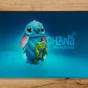 May include: Blue Stitch character holding a green frog with the text "Ohana Means Family" on a blue background.