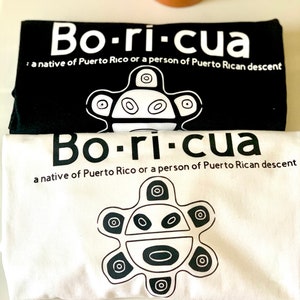 May include: Two t-shirts with the word "Bo-ri-cua" printed in white on a black background and black on a white background. The shirts also feature a stylized symbol of a sun with a face.