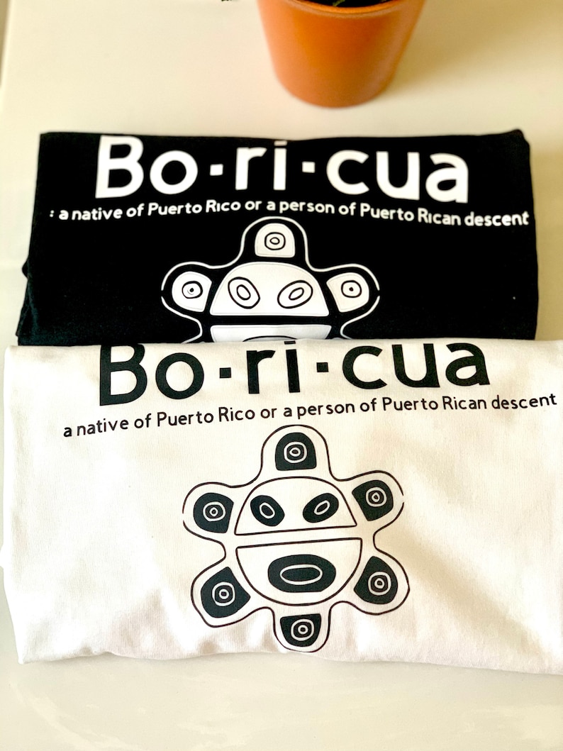 May include: Two t-shirts with the word "Bo-ri-cua" printed in white on a black background and black on a white background. The shirts also feature a stylized symbol of a sun with a face.
