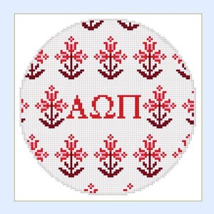 May include: A PDF stitch guide by t.b. designs featuring a circular cross-stitch pattern. The design displays a repeating grid of small red and dark red floral motifs surrounding the Greek letters Alpha, Omega, and Pi in the center.
