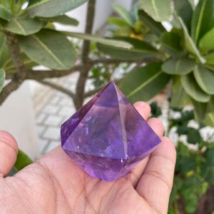 May include: A purple amethyst crystal shaped like a pyramid. The crystal is smooth and polished, with a deep purple color.