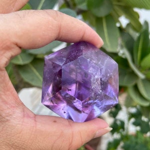 May include: A purple amethyst crystal shaped like a geometric hexagon. The crystal is clear and has a slight shimmer.