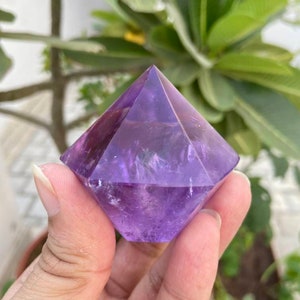 May include: A purple amethyst crystal shaped like a pyramid with multiple facets.
