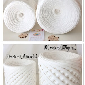 May include: Two white yarn balls, one measuring 50 meters (54.6 yards) and the other 100 meters (109 yards). The yarn is a thick, chunky texture. The yarn balls are sitting on a white surface with a small wooden leaf decoration next to each ball.
