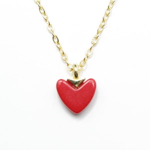 May include: A gold chain necklace with a red heart pendant.