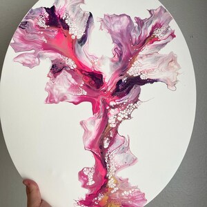 May include: Abstract painting on a round canvas with pink, white, and purple swirls and gold accents.