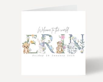 May include: A white card with the text "Welcome to the world ERIN" in blue script. The name ERIN is in large green letters with floral embellishments and small animal illustrations. The date "Friday 26 January 2024" is printed below the name.