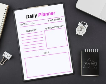 May include: A white daily planner with a black clip board, a black and white notepad with the word "MOCKUP" on it, and a white alarm clock. The planner has the words "Daily Planner" at the top and has sections for "To Do List", "Quote of the Day", and "Note".