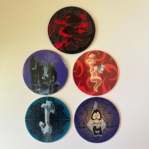May include: Five circular tokens featuring various designs. The top token is black with red accents. The middle left shows a dark house, the middle right a ghost on red. The bottom left features a blue ghost, and the bottom right a surprised ghost face.