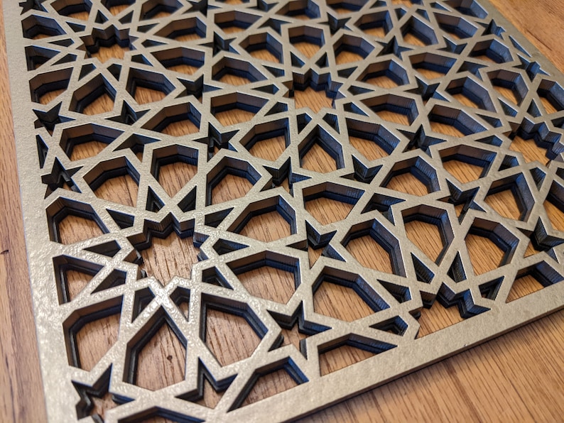 K&ouml;nnte beinhalten: Eine dekorative Holz-Wandverkleidung mit einem geometrischen Muster aus &uuml;berlappenden Sternen. Die Verkleidung ist aus hellbraunem Holz gefertigt und hat eine silberne Oberfl&auml;che.