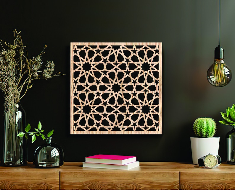 K&ouml;nnte beinhalten: Eine Wanddekoration aus Holz mit einem geometrischen Muster aus Sternen und filigranen Designs. Die Dekoration ist hellbraun und quadratisch.