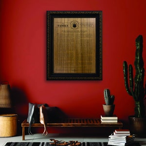 May include: A framed proclamation on a wood background with the text "A Proclamation to the World on the Family" and a black and white image of a temple. The frame is black with gold accents. The proclamation is hanging on a red wall.