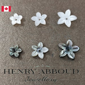 May include: Six white and black mother-of-pearl flower-shaped buttons with a hole in the centre. The buttons are arranged in two rows of three. The text "HENRY ABBOUD Jewellery" is at the bottom of the image.