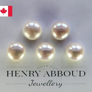 May include: Five white round pearls on a white surface. The pearls are smooth and shiny. The text "HENRY ABBOUD Jewellery" is visible at the bottom of the image.