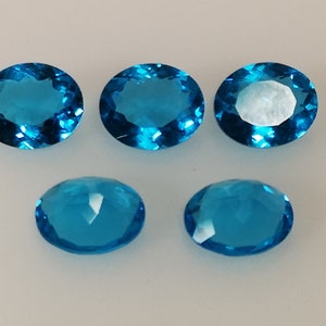 May include: Six oval-shaped, faceted, blue gemstones. The gemstones are arranged in two rows of three.