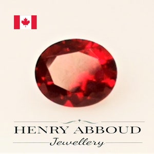 Peut inclure: Une pierre précieuse rouge foncé, ronde et facettée. La gemme est au centre, sur un fond neutre. Le texte "HENRY ABBOUD Jewellery" est au bas de l'image. Un drapeau canadien est dans le coin supérieur gauche.