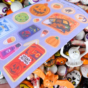 May include: A sheet of Halloween-themed stickers featuring pumpkins, candy corn, and spooky beverages. The stickers are on a light purple background with a spiderweb design. The words "Spooky Fruit Punch" are visible on one sticker.