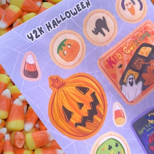 May include: A sheet of Halloween-themed stickers with a light purple background and a spiderweb design. The stickers feature pumpkins, ghosts, candy corn, and the text "Y2K Halloween" and "Kid Crizine".