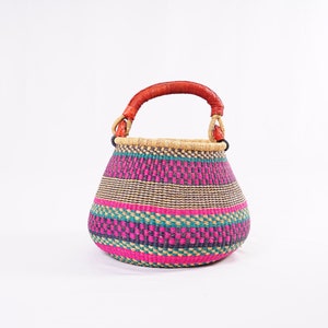 Peut inclure: Un panier tissé avec un motif rayé rose, vert et marron et une poignée en cuir marron.