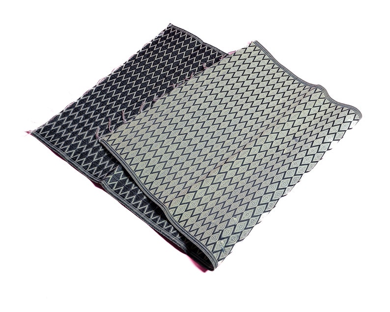 May include: Two woven mats with a diamond pattern. One mat is black with a white diamond pattern and the other is light green with a black diamond pattern.