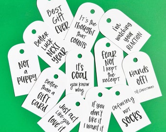 May include: Ten white gift tags with black text. The tags have various humorous sayings, such as "It's the thought that counts", "Better luck next year", and "Definitely not socks".