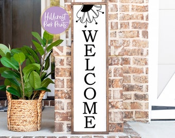 May include: A wooden welcome sign with a black and white floral design at the top and the word "WELCOME" in large black letters.