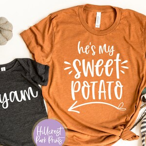May include: Two shirts with a fall-themed design. The larger shirt is orange and says "He's my sweet potato" with an arrow pointing to the left. The smaller shirt is gray and says "I yam".