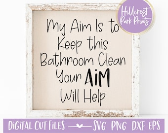 May include: A white framed sign with the text "My Aim Is to Keep this Bathroom Clean Your AiM Will Help" on a beige background.