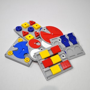 May include: A set of six colourful puzzle pieces made of plastic. The pieces are in various shapes and sizes, and they are all designed to fit together. The pieces are red, yellow, blue, and white.