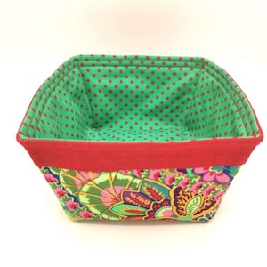 May include: A green and red fabric storage basket with a floral pattern. The basket is lined with a red and white polka dot fabric.