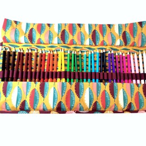 May include: A colorful set of colored pencils rolled up in a fabric case with a leaf pattern. The case is yellow, green, red, and brown.