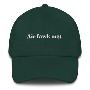 May include: A dark green baseball cap with white embroidered text that reads "Air fawk môt".