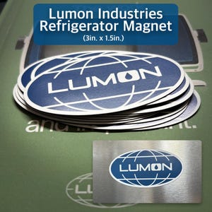 May include: A stack of oval-shaped Lumon Industries refrigerator magnets, each with a blue and white logo. The magnets are approximately 3 inches by 1.5 inches. A metal magnet with the same logo is also shown.