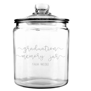 May include: A clear glass jar with a lid, labeled "graduation memory jar" and "TALIA NICOLE".
