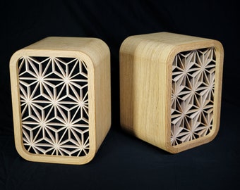 May include: Two wooden speaker boxes with a geometric pattern cut out of the front. The boxes are made of light wood and have a rounded top and bottom.