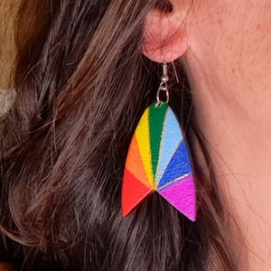 May include: A pair of rainbow-coloured earrings. The earrings are shaped like a stylized triangle with a silver hook. The colours include red, orange, yellow, green, blue, and purple. A unique and eye-catching accessory.