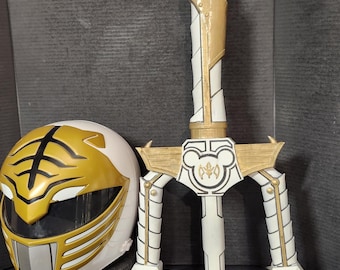 May include: A white and gold prop weapon and helmet set. The weapon has a three-pronged blade and a handle with a Mickey Mouse emblem. The helmet is white with gold accents and a visor. The set is likely for cosplay or display.