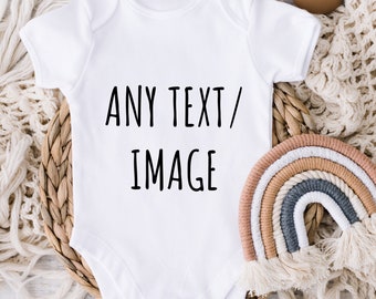 May include: White baby onesie with short sleeves and snaps at the bottom. The onesie has the text "ANY TEXT/IMAGE" printed on the front.