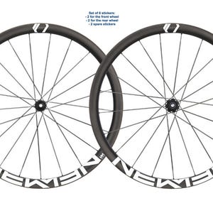 May include: Two black bicycle wheels with silver spokes. The rims feature white lettering reading "NEWMEN". The image includes text: "Set of 6 stickers: -2 for the front wheel -2 for the rear wheel -2 spare stickers."