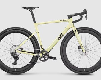 Könnte beinhalten: Ein cremefarbenes Gravelbike mit Carbonrahmen und schwarzem ROSE- sowie BACKROAD-Schriftzug. Das Fahrrad ist mit schwarzen Hochprofil-Laufrädern, einem schwarzen Rennlenker, einer schwarzen Sattelstütze und einem schwarzen Antrieb mit Scheibenbremsen ausgestattet.