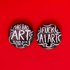Puede incluir: Dos botones redondos negros con texto blanco y rojo sobre fondo rojo. Uno dice "MAKE BAD ART, IT'S ALWAYS BETTER THAN AI". El otro dice "FUCK AI ARTS".
