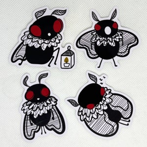 May include: Four black and white moth stickers with red eyes. The moths have a white, frilly collar and are in different poses. One moth is holding a small, yellow lantern.