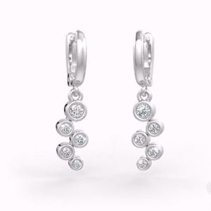 May include: Silver hoop earrings with a dangling cluster of five small round clear stones.