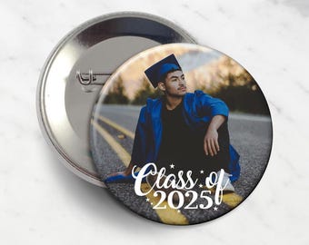 May include: A round, silver button with a pin back. The button features a photograph of a person in a graduation gown and cap, with the text "Class of 2025" in white script.
