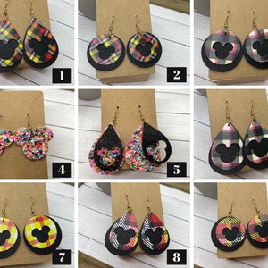 May include: Nine pairs of dangle earrings featuring a black Mickey Mouse silhouette on a variety of patterned backgrounds, including plaid, glitter, and polka dots. The earrings are numbered 1 through 9.