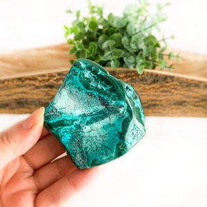 May include: A large, green and white, irregularly shaped, polished malachite crystal. The crystal has a banded pattern of green and white.
