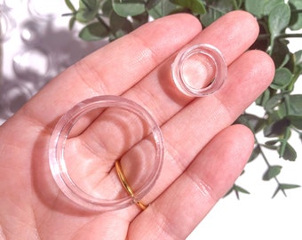 May include: Two clear plastic rings of different sizes. The larger ring is about 10 cm in diameter and the smaller ring is about 5 cm in diameter.
